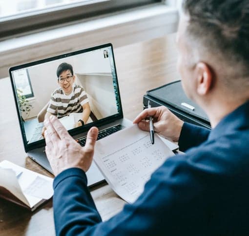 two men in a virtual meeting on laptops